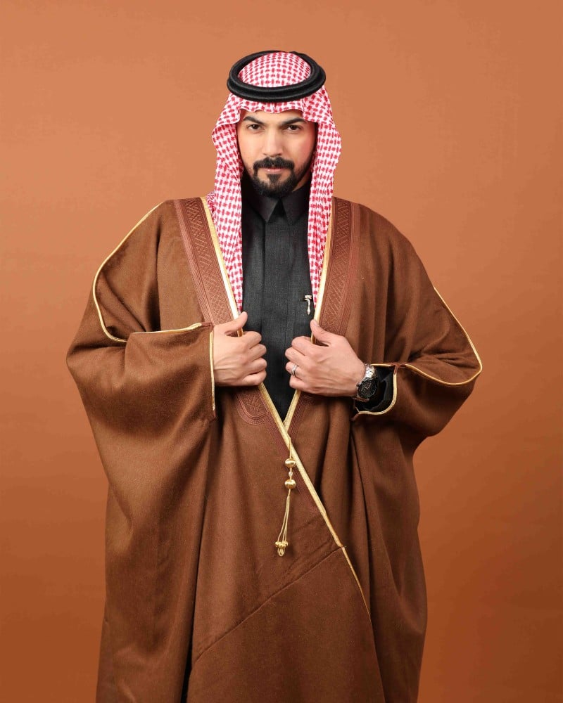 رجل يرتدي بشتاً شتوياً بلون أشقر مائل إلى البني بحواف ذهبية مع شماغ أحمر (2 من 2)