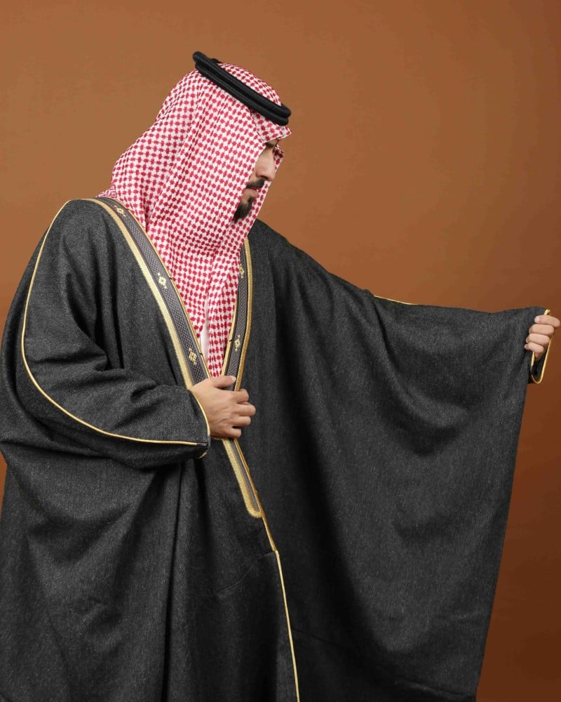 رجل يرتدي مشلحاً شتوياً رمادياً بحواف ذهبية وتطريز حريري مع شماغ أحمر (2 من 2)