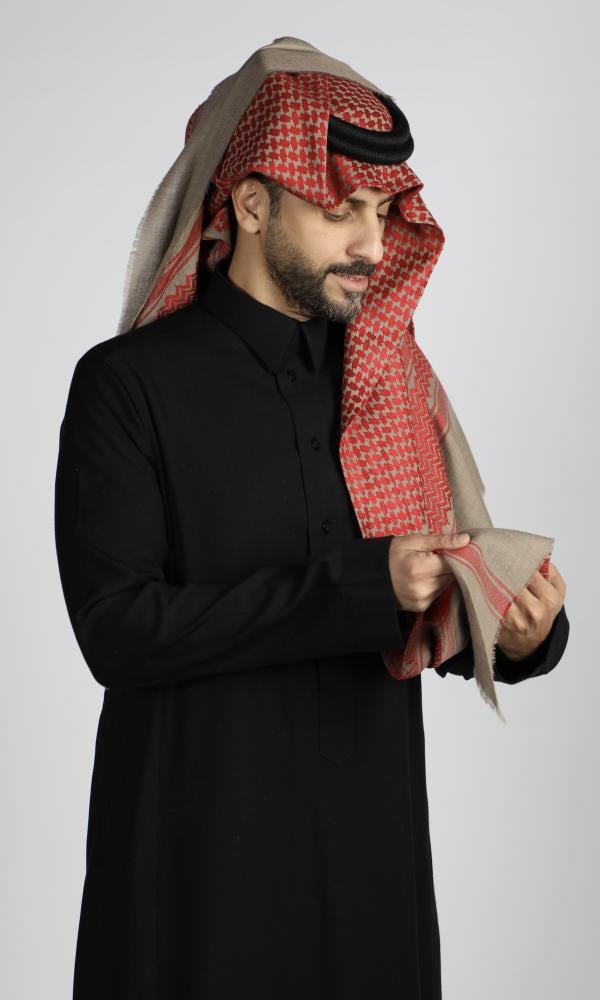 رجل يرتدي شماغاً كشميرياً شتوياً بنقش أحمر على أرضية بيج غامقة مع ثوب أسود (2 من 4)